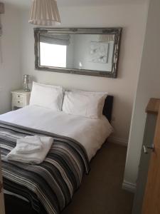 uma cama com lençóis brancos e um espelho na parede em Drake's Den by PureServiced em Plymouth
