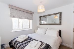 um quarto com uma cama com lençóis brancos e um espelho em Drake's Den by PureServiced em Plymouth