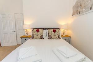a bedroom with a white bed with two lamps at Raleigh by Pureserviced in Plymouth