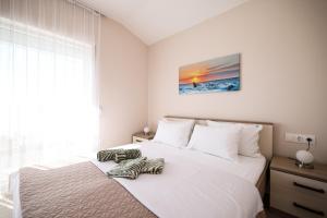 a white bedroom with two beds and a window at Apartments Anka with Seaview in Vrsi