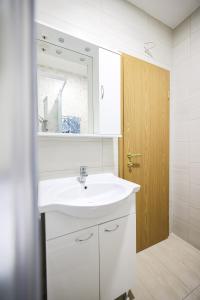 a white bathroom with a sink and a mirror at Apartments Anka with Seaview in Vrsi