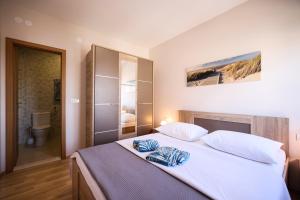 a bedroom with a large white bed and a bathroom at Apartments Anka with Seaview in Vrsi