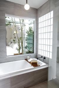 een badkamer met een groot raam en een bad bij La Kana Boutique Villa in Kamphaeng Phet