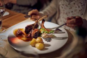 una persona seduta a un tavolo con un piatto di cibo di Hôtel de l'Ange a Nyon