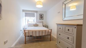 ein Schlafzimmer mit einem Bett, einem Spiegel und einer Kommode in der Unterkunft Tamar View by Pureserviced in Plymouth