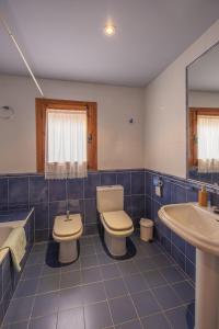 La salle de bains est pourvue de carrelage bleu, de toilettes et d'un lavabo. dans l'établissement Casas Santos y Tolta, à Loarre