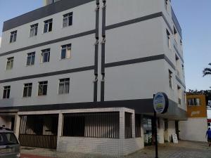 een hoog wit gebouw met een bord ervoor bij Apartamento na quadra do mar da Praia do Morro! in Guarapari