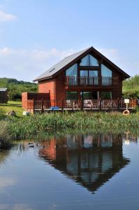 a house with a reflection in the water at Swallow Lodge with Hot Tub, dogs welcome sleeps 8, Great resort Facilities in Padstow