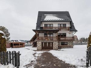 duży drewniany dom z śniegiem na ziemi w obiekcie Dom Na Borku w mieście Ciche