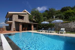 een zwembad met stoelen en parasols naast een huis bij Villa Etna Mare - Pool villa in peaceful location with breathtaking views of the sea, Mt Etna & Taormina - in Taormina