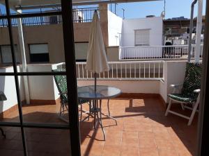 a balcony with a table and an umbrella on a balcony at Casa Angelus + in Águilas