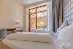 two beds in a bedroom with a window at TATRA SUITES Senior Lux Apartment C413 in Smokovce