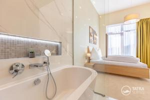 a white bathroom with a tub and a bed at TATRA SUITES Senior Lux Apartment C413 in Smokovce +17 photos