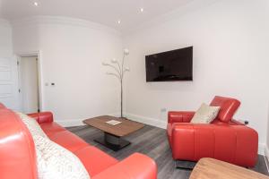 a living room with red furniture and a flat screen tv at The Balmoral Suite in Plymouth