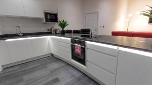 a kitchen with white cabinets and a black counter top at The Balmoral Suite in Plymouth