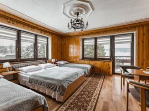 a bedroom with two beds and a chandelier and windows at Dom Na Borku in Ciche