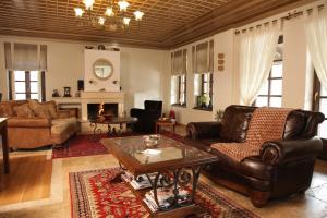 a living room with leather furniture and a fireplace at Arxontiko Krana in Asprangeloi