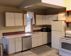 a kitchen with white cabinets and a white refrigerator at Nugget Place-Includes three separate two bedroom units near Mendenhall Glacier-DISCOUNTS ON TOURS! in Mendenhaven
