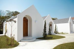 a white house with a brown door at La Kana Boutique Villa in Kamphaeng Phet