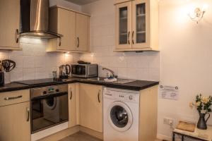 a kitchen with a washing machine and a microwave at The Beachut by Pureserviced in Plymouth
