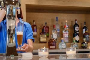 a person holding a glass of beer behind a bar at Staybridge Suites Rochester - Mayo Clinic Area, an IHG Hotel in Rochester
