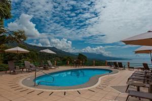 a swimming pool with chairs and umbrellas on a patio at Villas Alturas in Dominical