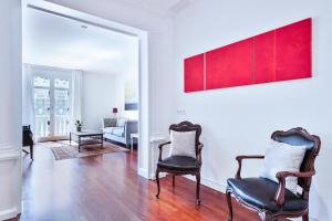 una sala de estar con 2 sillas y una pintura roja en la pared en Milton House Gran Via, en Barcelona
