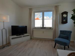 a living room with a television and a chair and a window at Ferienwohnung Frieda - a63776 in Bad Sachsa