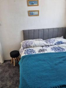 a bedroom with a bed with a blue blanket and a stool at Charming 2 Bedroom Holiday Chalet in Withernsea