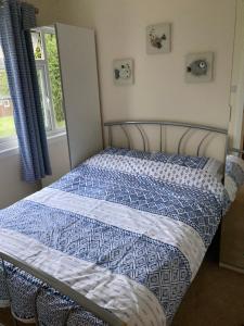 a bed with a blue and white comforter and a window at 13 The Park in Kilkhampton