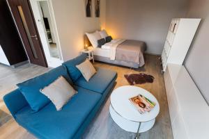 sala de estar con sofá azul y cama en Golden Apartments Rezidence Nová Karolina II., en Ostrava