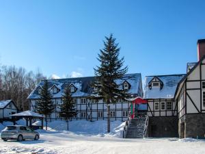 uma casa com um carro estacionado na neve em Petit Hotel Gracey Tomamu em Shimukappu