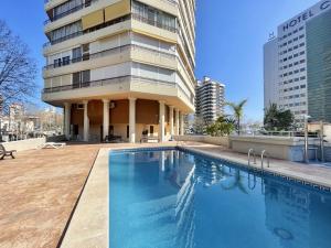 un bâtiment avec une piscine en face d'un bâtiment dans l'établissement TORRE VALENCIA LEVANTE BEACH, à Benidorm