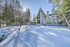 a house with a snow covered yard in front at Dreamy Lake Skegemog Retreat Boat, Ski and Sip! in Williamsburg