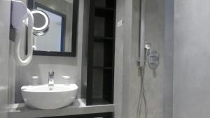ein Bad mit einem Waschbecken und einer Dusche mit einem Spiegel in der Unterkunft Logis Hôtel Saint Guirec Et De La Plage in Perros-Guirec