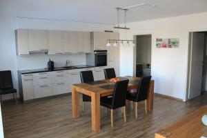 cocina y comedor con mesa de madera y sillas en Moderne 3-Zimmerwohnung, an Skipiste, mit Aussicht, en Flumserberg