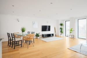 a living room with a table and chairs and a television at Riverside Two Bedroom Apartment in Canary Wharf in London