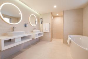 a bathroom with two sinks and a tub and mirrors at Maritim Antonine Hotel & Spa in Mellieħa