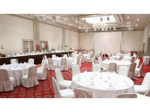 une salle de banquet avec des tables blanches et des chaises blanches dans l'établissement Boston Plaza Kusatsu Biwa Lake - Vacation STAY 15455v, à Kusatsu