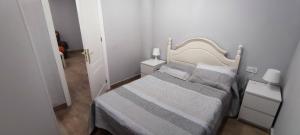 a small white bedroom with a bed and two night stands at APARTAMENTO HUERTA NUEVA in Málaga