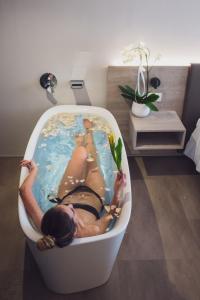 a woman is laying in a bath tub at GoTì Hotel in Nago-Torbole