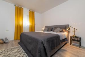 ein Schlafzimmer mit einem großen Bett und gelben Vorhängen in der Unterkunft D&A Superior Apartman in Rabac