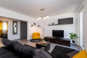 ein Wohnzimmer mit einem Sofa und einem TV in der Unterkunft D&A Superior Apartman in Rabac