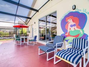 um quarto com cadeiras e uma parede com uma pintura de uma sereia em Ariel Private Pool Home Wspa em Orlando