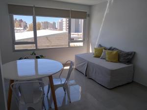 a bedroom with a bed and a table and a window at Departamento Marea III Puerto Madryn in Puerto Madryn