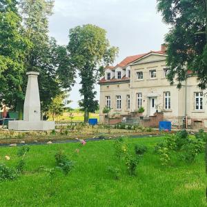 una casa con un monumento en la hierba delante de ella en Palac Osowo gostynskie en Gostyń