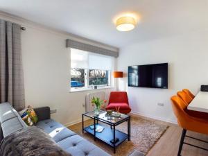 a living room with a blue couch and a red chair at Scotchacre Kingsbarns - Walk to Beach & Golf Club in Kingsbarns