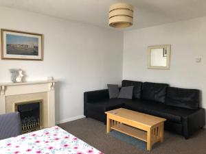a living room with a black couch and a fireplace at Thames View & free parking - perfect long stay workers only in London