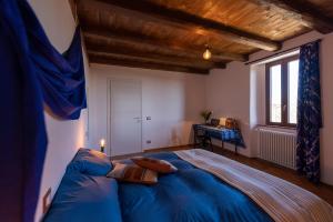 una camera da letto con un letto con lenzuola blu e una finestra di Cascina Fogona - Sport e Natura ad Altare