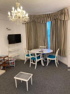 a living room with a table and chairs and a chandelier at Abingdon Owner Apartment 19 in Ryde